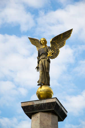 Statue of an angel on a high pedestal against the sky.の写真素材