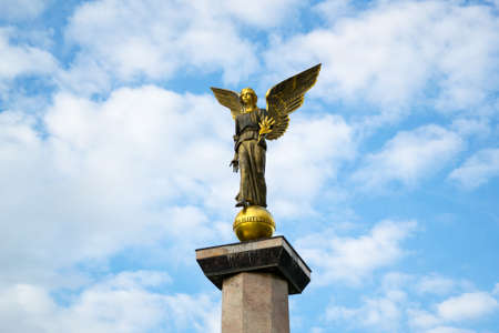 Statue of an angel on a high pedestal against the sky.の写真素材