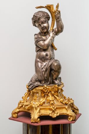Figurine of the half-naked boy kneeling on a gold pedestalの写真素材