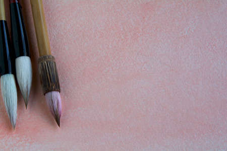 Chinese watercolor brushes on a pink-tinged watercolor sheet adorned with purple wildflowers.の写真素材