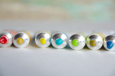 Tubes close-up with bright multi-colored watercolors blue, yellow, green shades. Good background for art publications.の写真素材