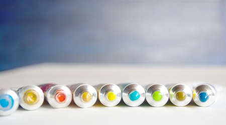 Tubes close-up with bright multi-colored watercolors blue, yellow, green shades. Good background for art publications.の写真素材