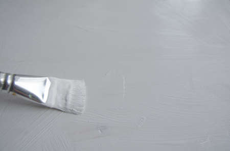 Priming of a wooden panel for painting with white acrylic primer using a bristle brush.の写真素材