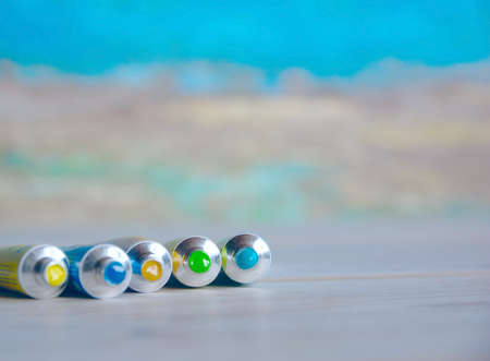 Tubes close-up with bright multi-colored watercolors blue, yellow, green shades. Good background for art publications.の写真素材