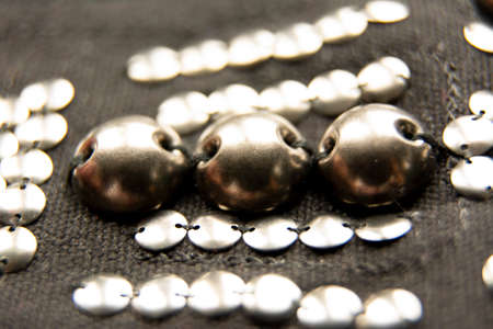 Silver shiny beads and sequins in vintage style are sewn on black coarse fabric.の写真素材