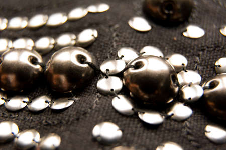 Silver shiny beads and sequins in vintage style are sewn on black coarse fabric.の写真素材