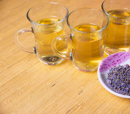 Herbal cold tea with lavender in glass cups on a yellow and red background.の写真素材
