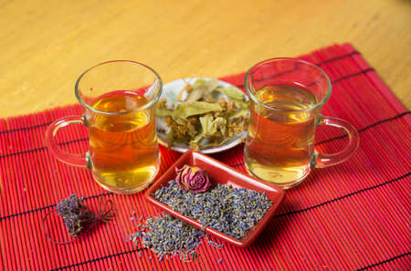 Herbal cold tea with lavender, linden and oregano in glass cups on a yellow and red background.の写真素材