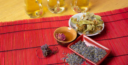Herbal cold tea with lavender, rose,linden and oregano in glass cups on a yellow and red background.の写真素材