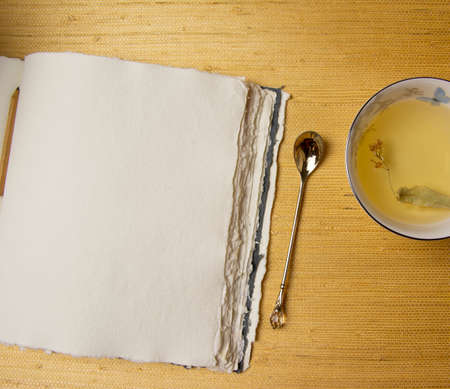 Handmade cotton notebook or sketchbook. Can be used as mocap. Nearby is a cup of herbal tea and dried flowers.の写真素材