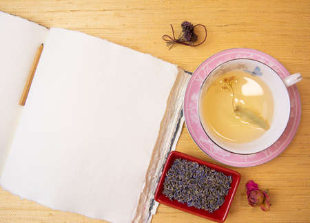 Handmade cotton notebook or sketchbook. Can be used as mocap. Nearby is a cup of herbal tea and dried flowers.の写真素材