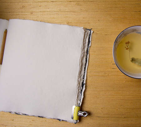 Handmade cotton notebook or sketchbook. Can be used as mocap. Nearby is a cup of herbal tea and dried flowers.の写真素材