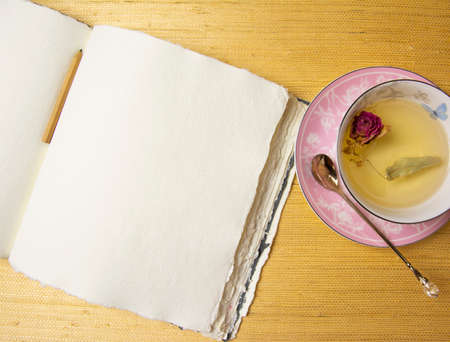 Handmade cotton notebook or sketchbook. Can be used as mocap. Nearby is a cup of herbal tea and dried flowers.の写真素材