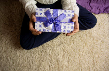 Christmas present in a beautiful box with a blue bow in children's hands.の写真素材