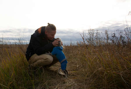 A middle-aged man walks with a dog breed Chinese Hairless Crested Dog on nature in autumn afternoon.の写真素材