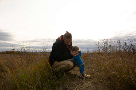 A middle-aged man walks with a dog breed Chinese Hairless Crested Dog on nature in autumn afternoon.の写真素材