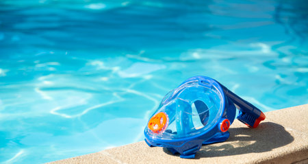 swimming mask with snorkel near the blue pool on a sunny tropical morningの写真素材