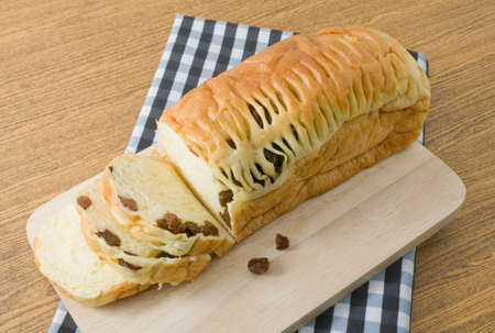 Cuisine and Food, A Homemade Slice Loaf of Brown Raisin Bread on Wooden Cutting Board.の写真素材
