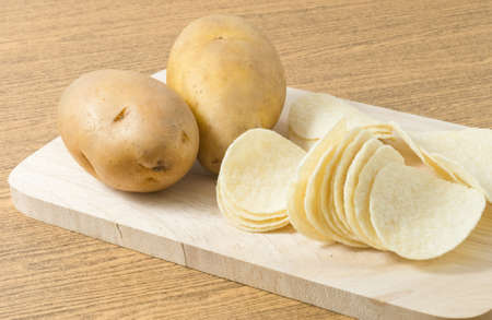 Snack Food, Potato Tuber with Potato Chips or Crisp on Wooden Cutting Board.の写真素材