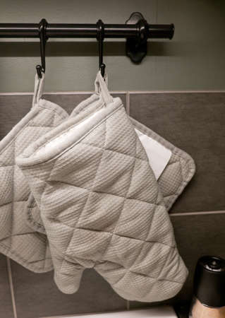 Kitchen Utensil, Grey Kitchen Glove and Potholder Hanging on The Wall Surface.の写真素材