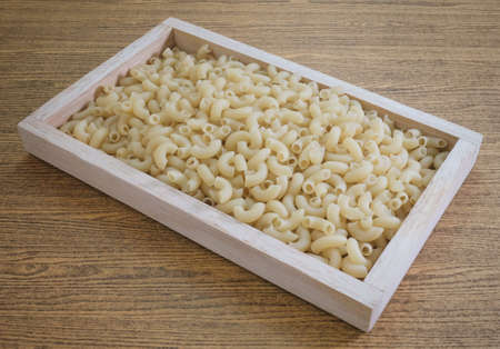 Food and Cuisine, Uncooked and Dried Elbow Macaroni or Gomiti Pasta in A Wooden Tray.の写真素材