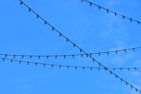 Row of Electric Light Bulbs Hanging on The Wire Against Beautiful Blue Sky.