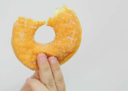 Food and Bakery, Hand Holding Delicious Fresh and Sweet Sugar Donut with Bite Missing on White Background.の写真素材