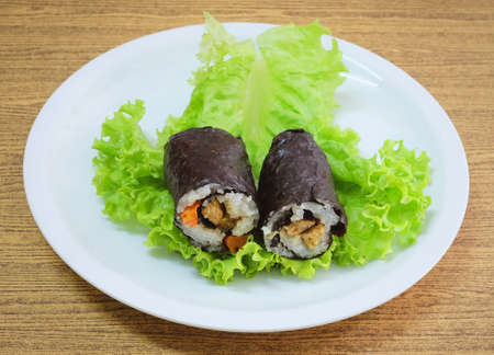 Japanese Cuisine, Traditional Vagetarian Japanese Rice Maki Sushi Roll Stuff with Tofu and Carrot Wrapped in Nori Seaweed Served on Green Oak.の写真素材