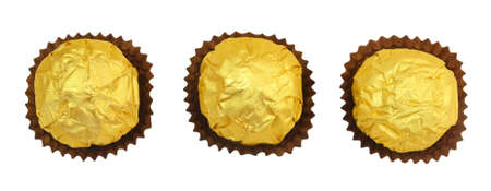 Sweet Food, Top View of Three Round Chocolate Candy Balls or Chocolate Bonbons in Golden Wrapper Isolated on White Background.の写真素材
