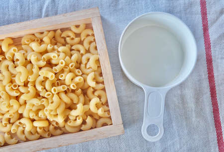 Food and Cuisine, Top View of Uncooked and Dried Elbow Macaroni Pasta in Wooden Tray with Plastic...