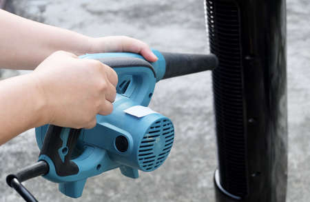 Person Using The Air Blower to Clean A Tower Fan, Use to Remove Dust From The Electrical Machine.の写真素材