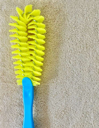 Close Up Yellow Plastic Cleaning Brush with Blue Handle Laying on Brown Towel, Used Wet with Wwater...
