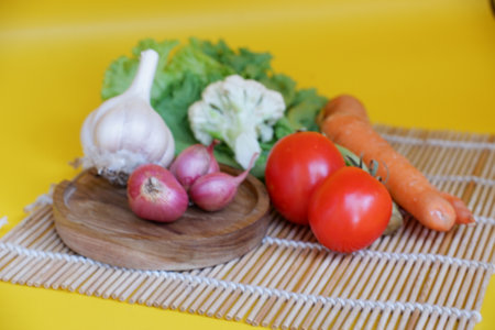 Vegetables on a wooden plate on a yellow background in the kitchenの写真素材