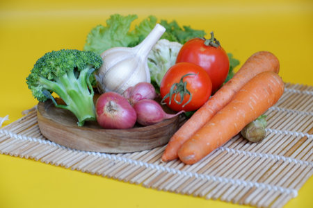Vegetables on a wooden plate on a yellow background. The concept of healthy eating.の写真素材