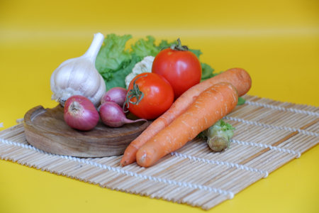 Fresh vegetables on a wooden board on a yellow background. Vegetarian food.の写真素材