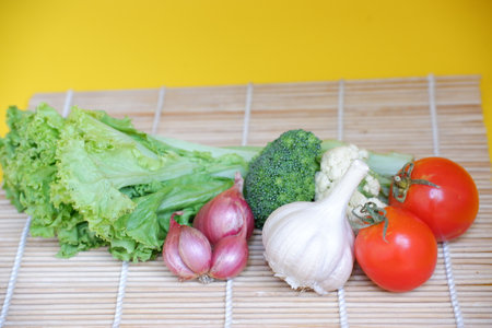 vegetables on a bamboo mat on a yellow background, healthy foodの写真素材