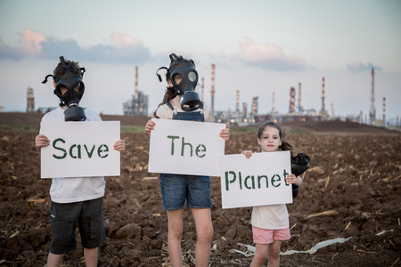 Save the plant. Young kids holding signs standing near a refinery with gas masksの写真素材
