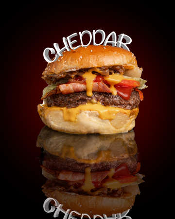 Burger with cheddar cheese, bacon and white letters on top of it.の写真素材