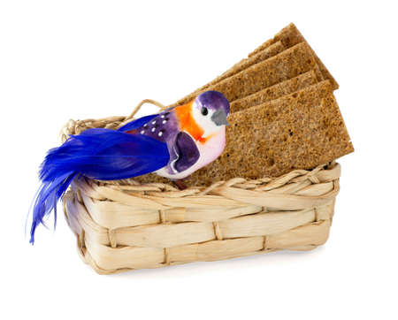 Bird on wicker basket with crackers on white backgroundの写真素材