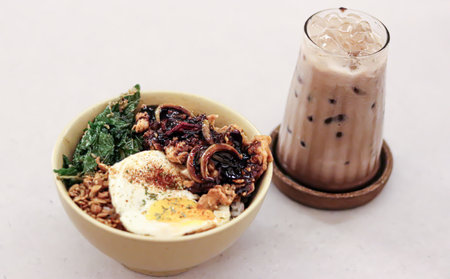a glass of coffee with ice and boiled noodles filled with eggs and vegetablesの写真素材