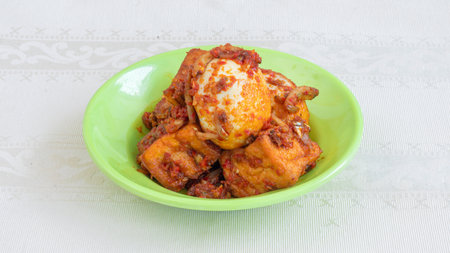 A plate of rice with egg Balado and long bean sauce, chili sauce filled with eggs, anchovies, and tofu. Served in a bowl on a gray background. Selected focus.の写真素材