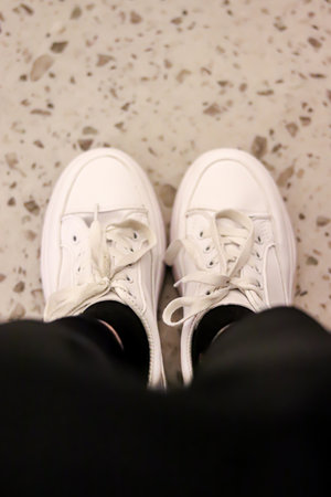 Fashionable white sneakers on female legs, close-up.の写真素材