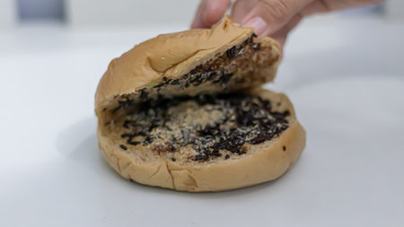 Woman hand holding a chocolate donut against a white backgroundの写真素材
