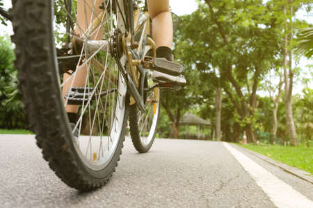 A woman riding a bicycle in the park in the evening