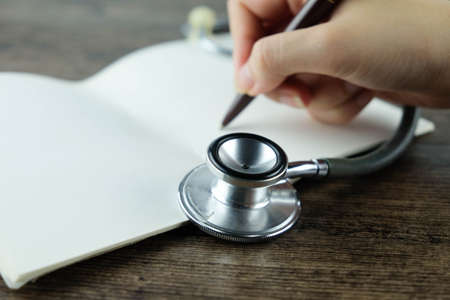 Close up of Stethoscope, and hand writing notebook, Concept for Medical Education or health recording.の写真素材
