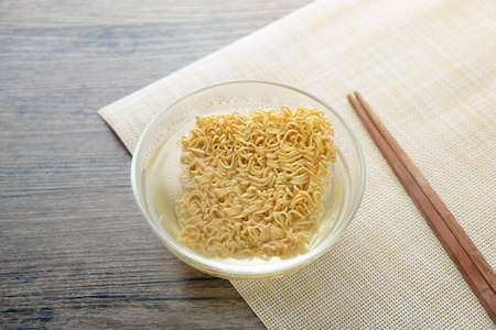 Glass bowl , chopsticks and instant noodle on the wooden tableの写真素材