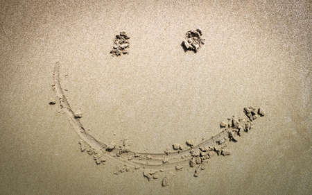 Top view of happy smiley face drawing on a sand at the beach.の写真素材