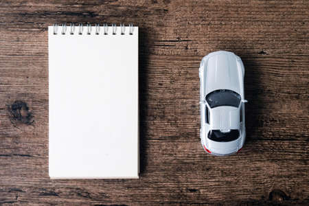 Top view image of blank page notebook and small car model on the wooden table.の写真素材