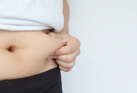 Side of woman hand catching fat body belly paunch , diabetic risk factor