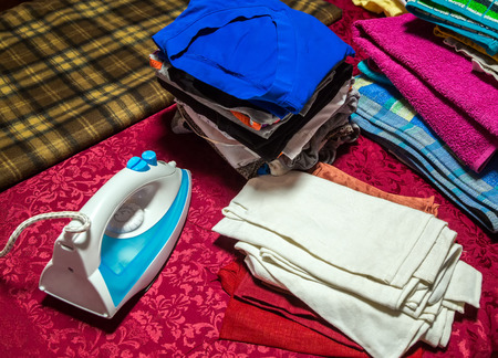 Blue iron on the ironing board with clothes and underwear, close-up view from the topの写真素材